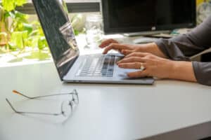 a person working at a laptop, glasses put on a table