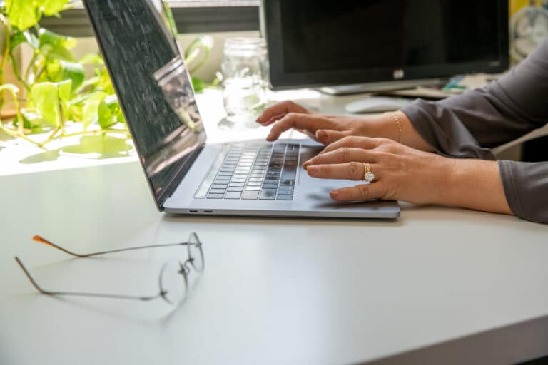 a person working at a laptop, glasses put on a table